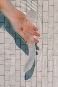 Load image into Gallery viewer, Clear clear quartz wand held by a hand on a tiled floor in a pool
