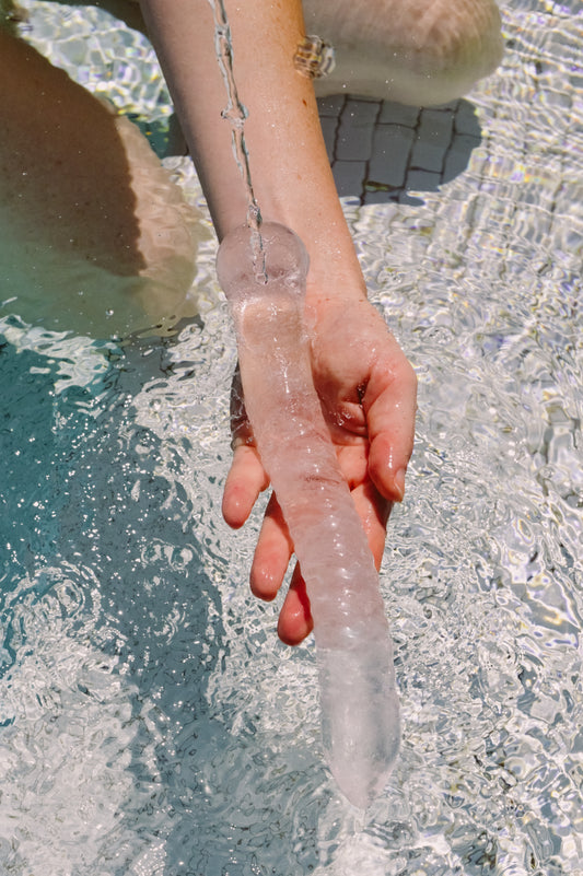 Person holding a clear quartz wand in water