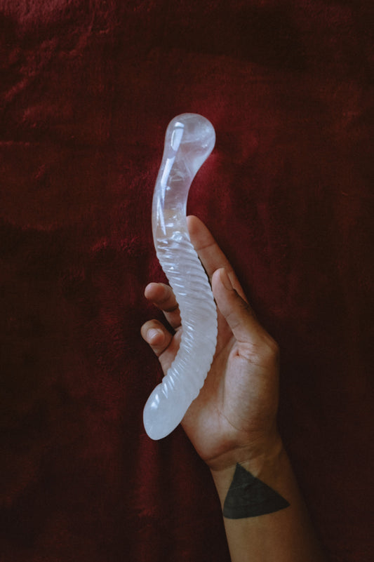 Hand holding a clear jellyfish-shaped object against a dark red background