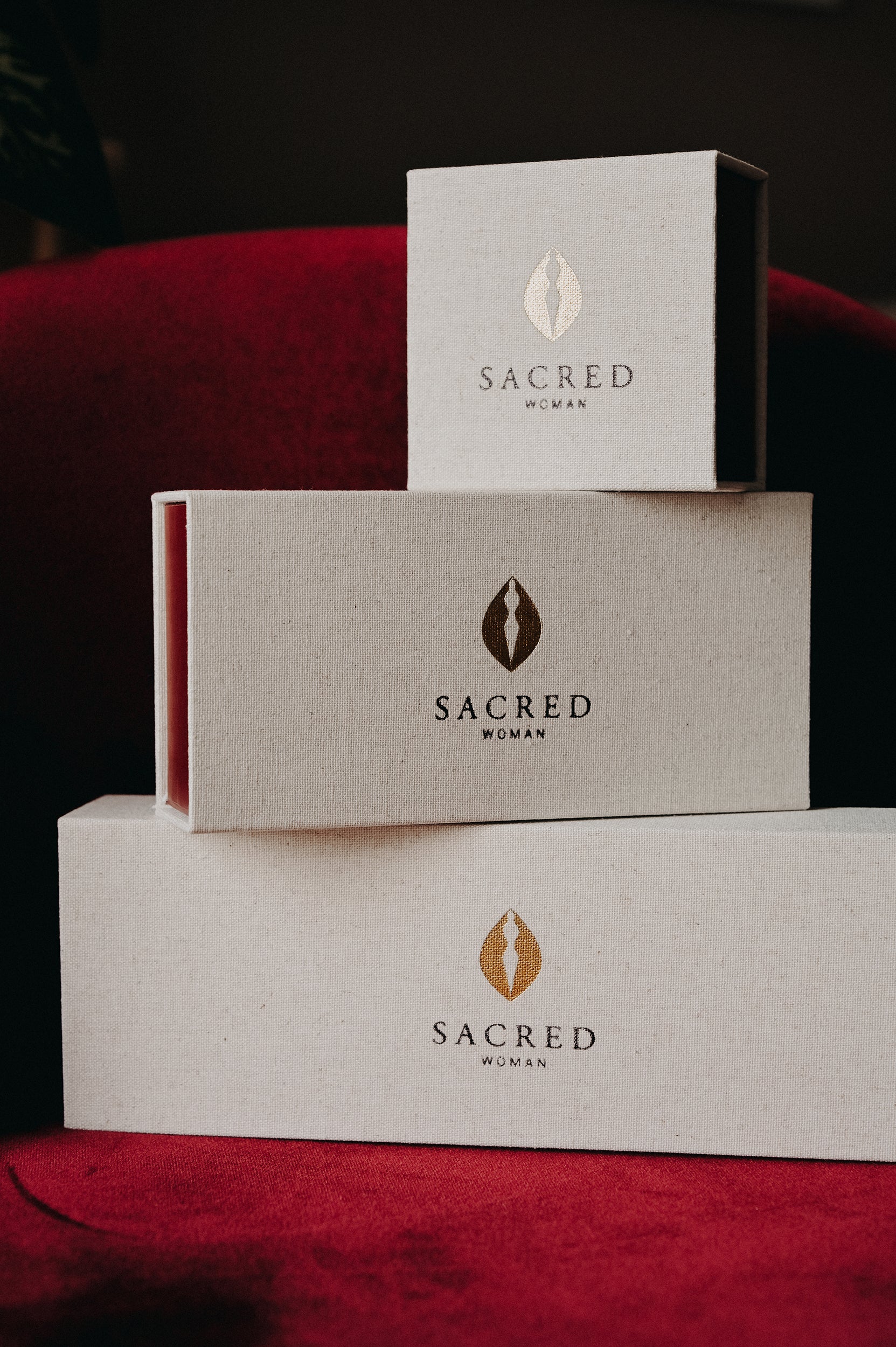 Stack of 'Sacred Woman' branded boxes on a red surface